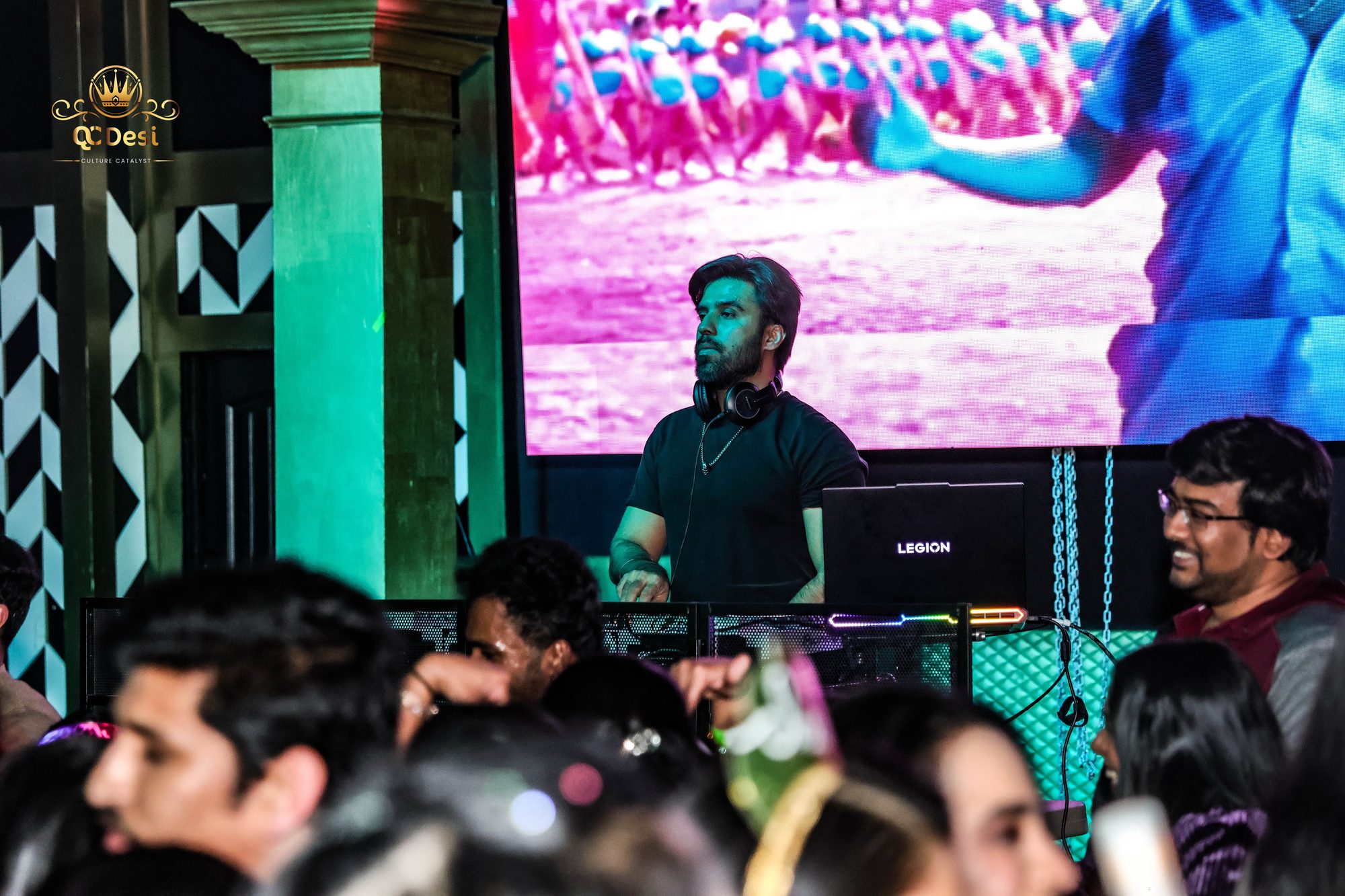 DJ playing to the crowd beside the video wall
